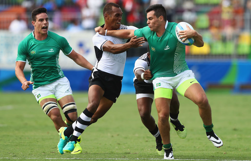 Daniel Sancery of Brazil and a teammate say hello to Fiji’s Osea Kolinisau during the Pool A match between Fiji and Brazil. Image via Getty.